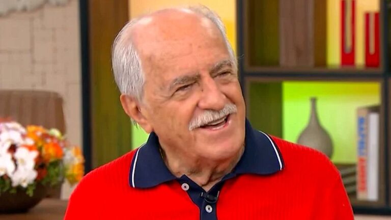 Ary Fontoura sorri durante participação em programa de TV em estúdio com cenário colorido