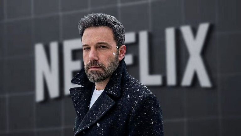 Homem de barba e casaco escuro aparece em frente a prédio com o logotipo da Netflix enquanto flocos de neve caem ao redor