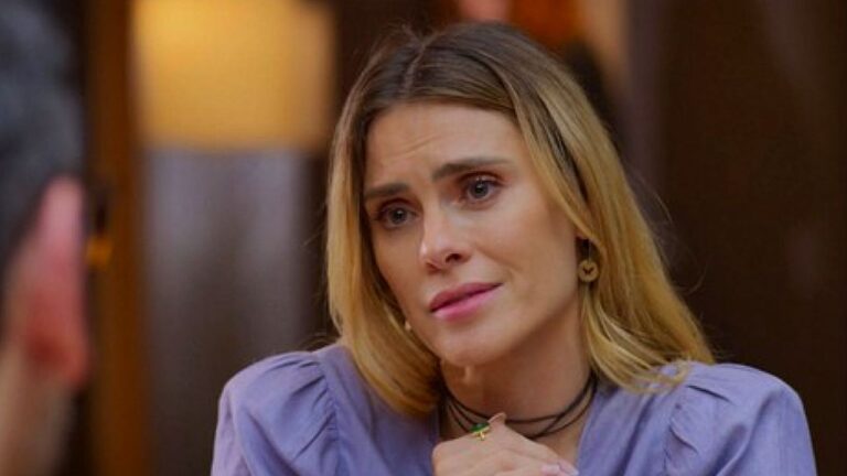 Carolina Dieckmmann em cena de novela conversa com homem em restaurante com expressão emocionada