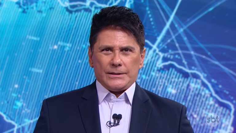 Cesar Filho, usando terno escuro e camisa clara, fala diretamente para a câmera em estúdio. Ao fundo, um telão exibe um mapa estilizado em tons de azul com linhas e gráficos, enquanto o logotipo do SBT aparece no canto da tela.