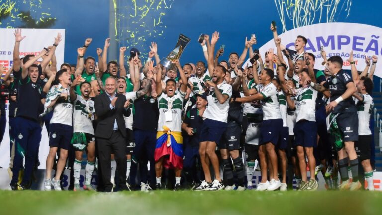 Jogadores do Coritiba celebram o título da Série B de 2025 no gramado, com atleta levantando o troféu dourado sob chuva de confetes e faixas festivas
