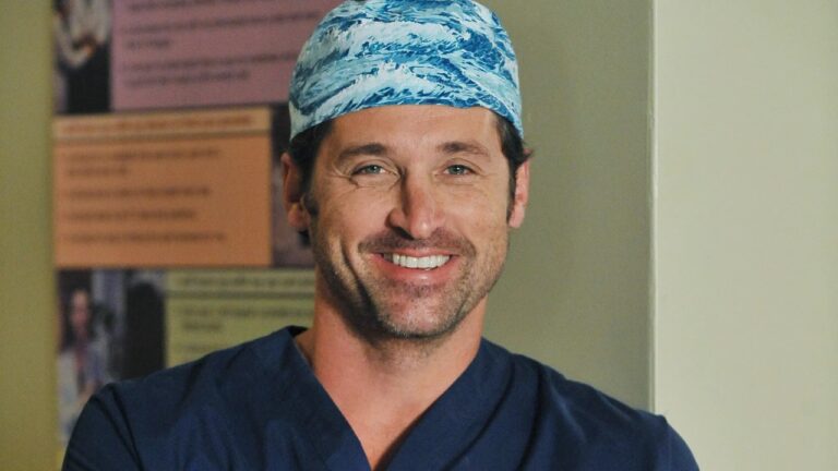 Derek Shepherd (Patrick Dempsey) com uniforme cirúrgico e braços cruzados em hospital na série Grey’s Anatomy