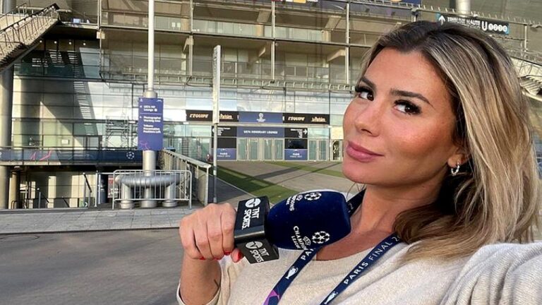 Repórter esportiva segura microfone da TNT Sports em frente a estádio durante cobertura da Champions League