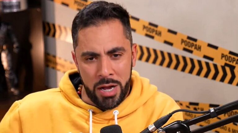 Homem de moletom amarelo fala ao microfone em estúdio de podcast com fundo decorado com fitas de isolamento