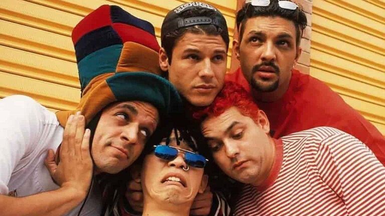 Integrantes da banda Mamonas Assassinas posam juntos com figurinos coloridos em imagem promocional do grupo dos anos 1990