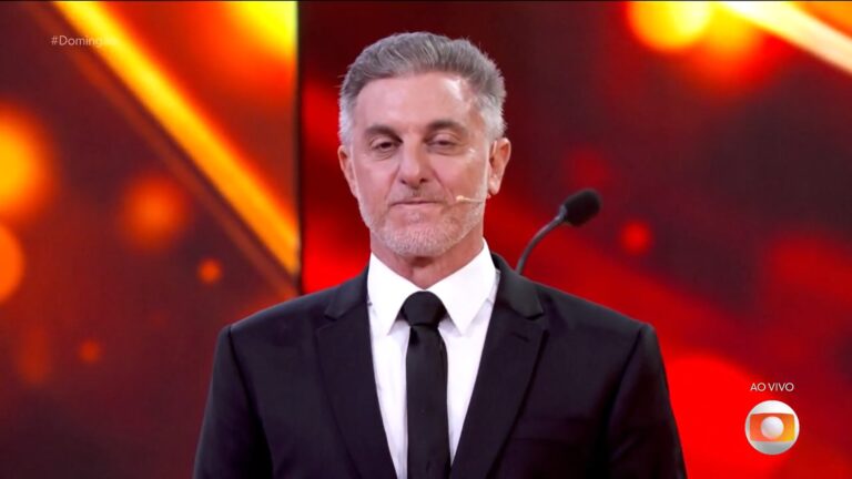 Luciano Huck de terno e gravata no palco do Domingão, durante a entrega do prêmio Melhores do Ano, ao vivo na TV Globo.