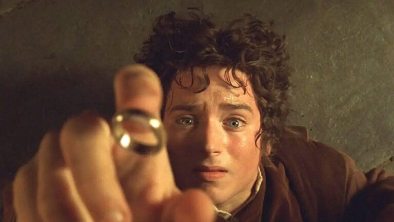 Personagem segura anel e observa com expressão apreensiva em cena de O Senhor dos Anéis