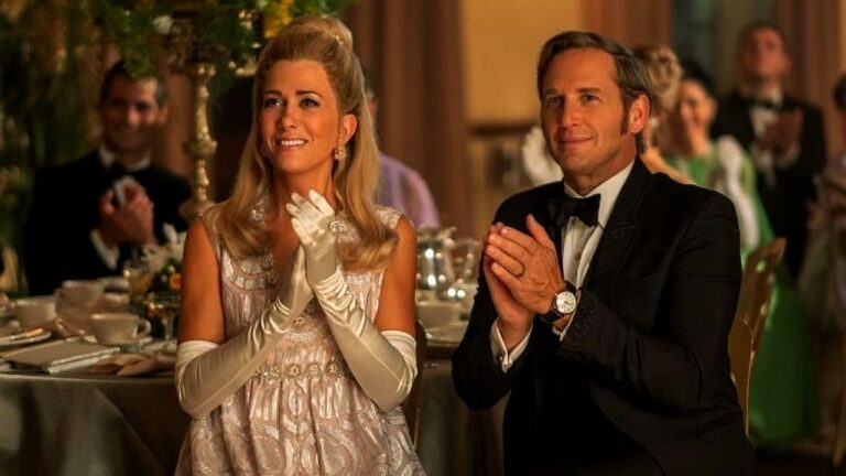 Casal elegante aplaude durante evento formal em salão luxuoso com convidados ao fundo