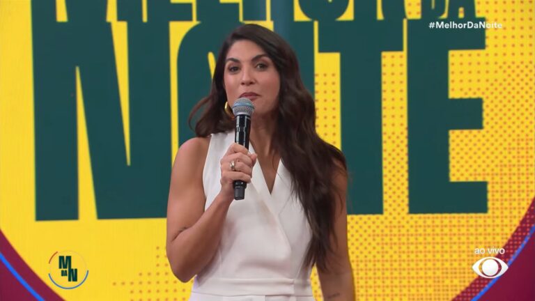 Pâmela Lucciola segura um microfone e fala ao vivo em estúdio com fundo colorido e o título do programa Melhor da Noite; na tela aparecem a hashtag do programa e o logotipo da Band.