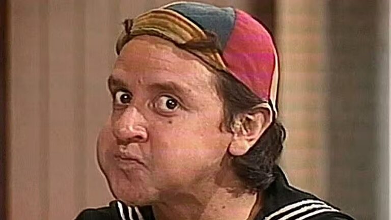 Quico com boné colorido e expressão surpresa em cena do seriado Chaves