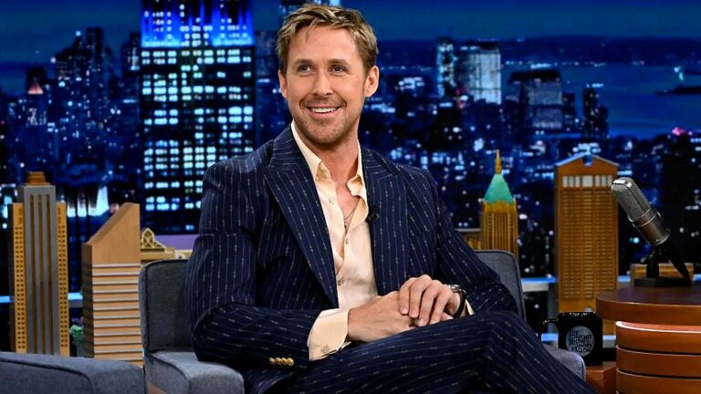 Ryan Gosling participa de entrevista em talk show com cenário urbano iluminado ao fundo
