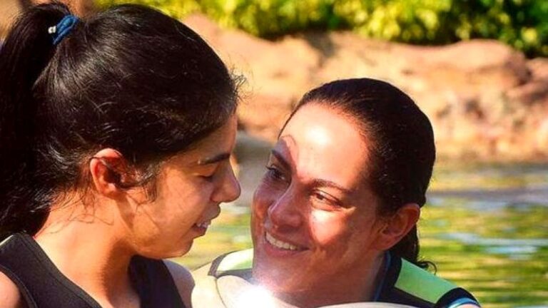 Duas mulheres se encaram e sorriem dentro de rio em momento íntimo ao ar livre
