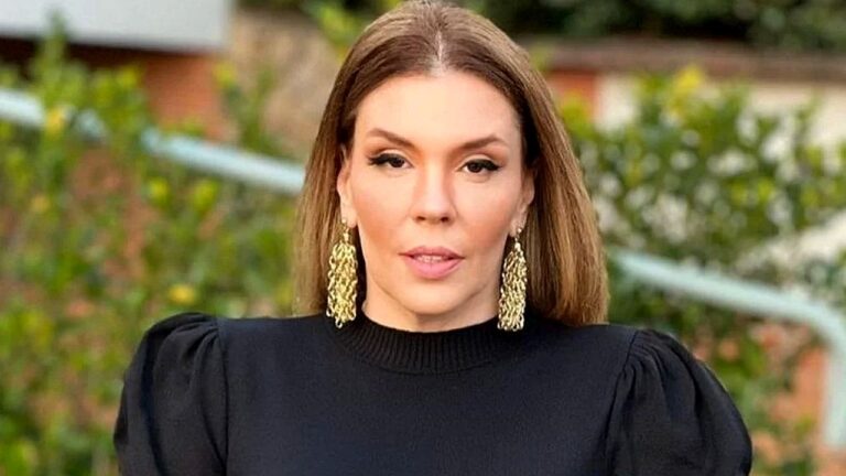 Mulher de blusa preta e brincos dourados fala em vídeo ao ar livre com vegetação desfocada ao fundo