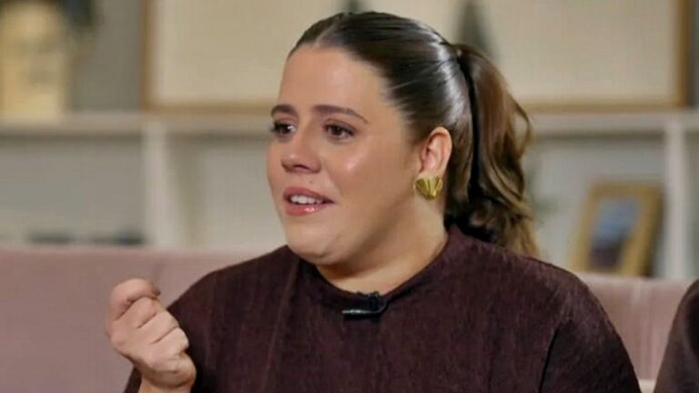 Mulher com cabelo preso em rabo de cavalo fala emocionada durante entrevista em programa de televisão em estúdio