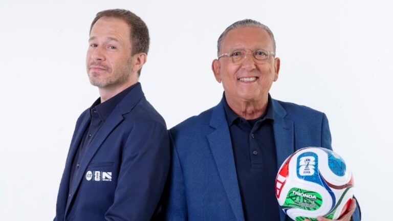 Tiago Leifert e Galvão Bueno vestem paletós azuis sobre fundo branco, Galvão sorri segurando bola da Copa do Mundo, logotipos SBT e Sports em destaque