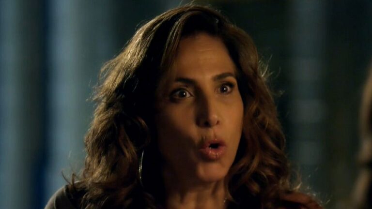 Mulher com expressão surpresa fala em cena noturna com fundo desfocado