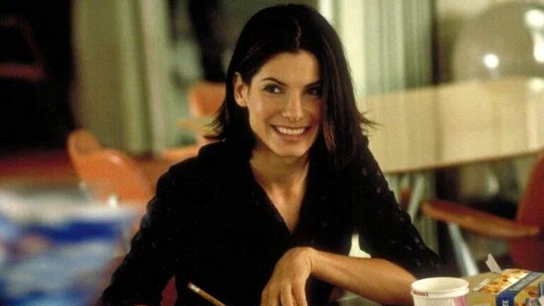 Mulher sorri enquanto segura hashis sentada à mesa em restaurante em cena de filme