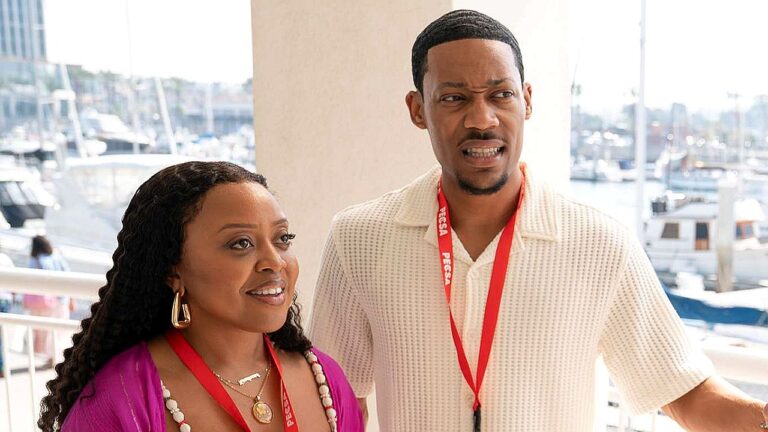 Casal com crachás observa algo surpreso em marina com barcos ao fundo durante evento ao ar livre