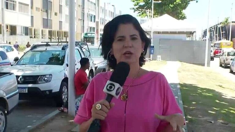 Repórter segura microfone da TV Globo e fala ao vivo em rua com carros estacionados ao fundo