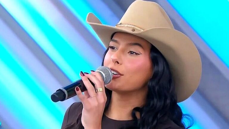 Cantora com chapéu country segura microfone durante apresentação em programa de TV