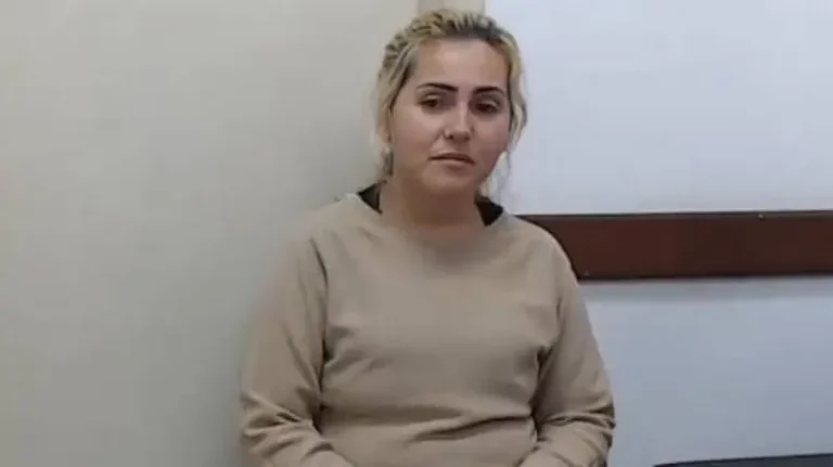 Ana Paula Veloso Fernandes sentada em sala com parede clara ao fundo usando blusa bege e olhando para a câmera