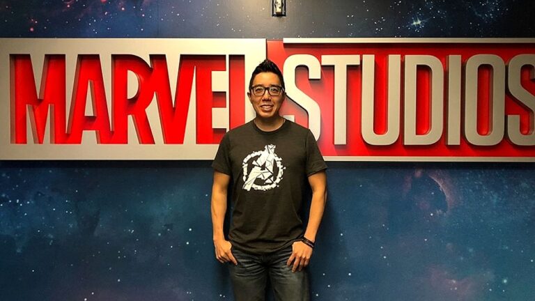 Homem posa diante do letreiro Marvel Studios em parede com fundo espacial em estúdio de cinema