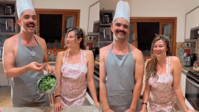 Bella Mantovani e Vagner Macedo em cozinha usando aventais e chapéu de chef enquanto preparam alimento e posam sorrindo