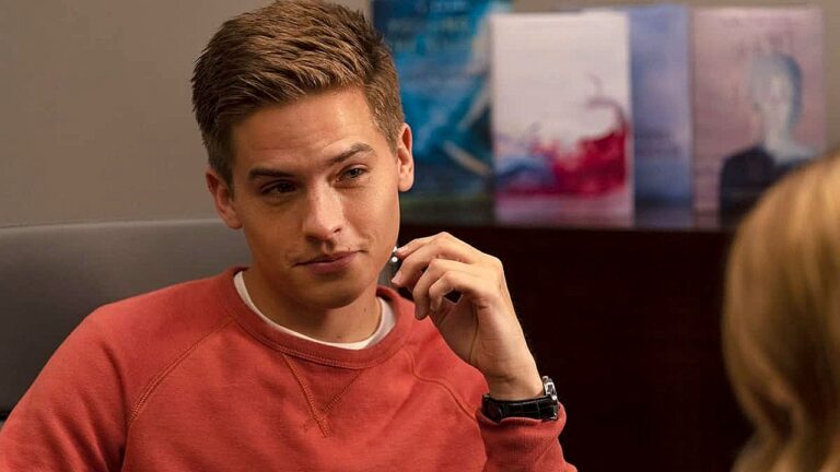 Homem jovem de suéter vermelho segura fone e olha atento durante conversa em ambiente interno