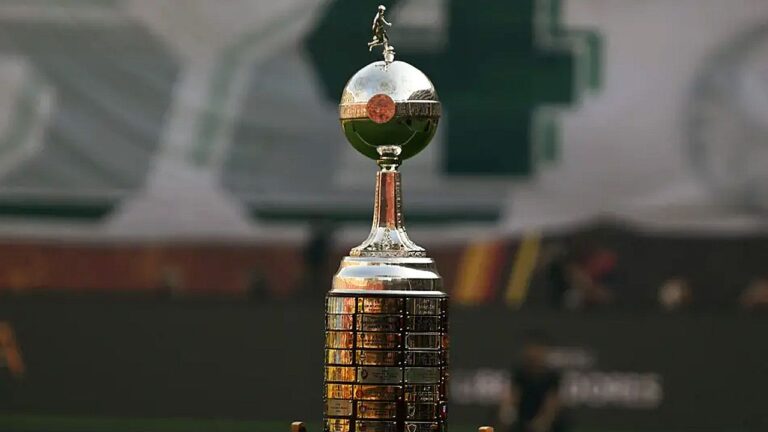 Taça da Libertadores exibida em campo antes de partida com estádio ao fundo
