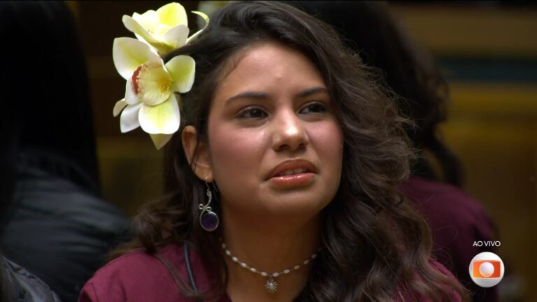 Gabriela Saporito, com flor no cabelo e colar, tensa antes de sua eliminação do BBB 26, reality show da TV Globo.