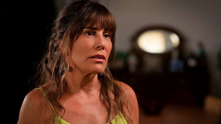 Mulher com expressão séria olha para o lado em cena dramática ambientada em interior com iluminação suave