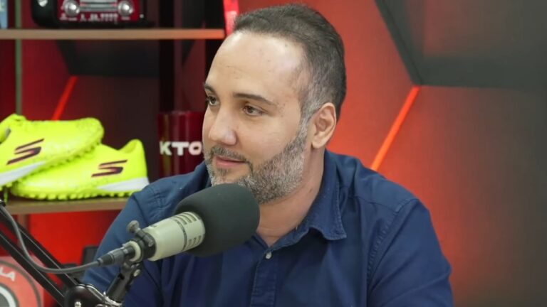 Jorge Iggor fala ao microfone em estúdio de podcast com prateleira ao fundo e chuteiras expostas