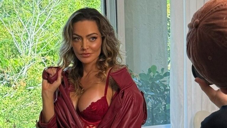 Laura Keller posa com lingerie vermelha e robe aberto durante ensaio fotográfico em ambiente interno com fotógrafo ao lado