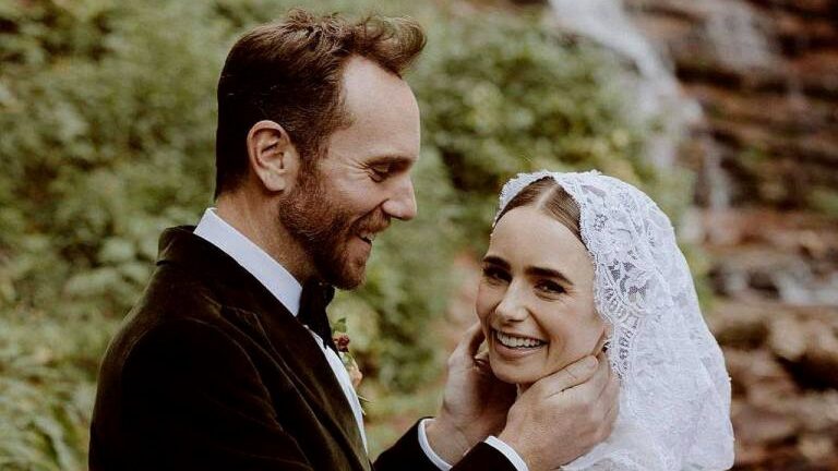 Noivo segura o rosto da noiva sorridente com véu durante cerimônia de casamento ao ar livre