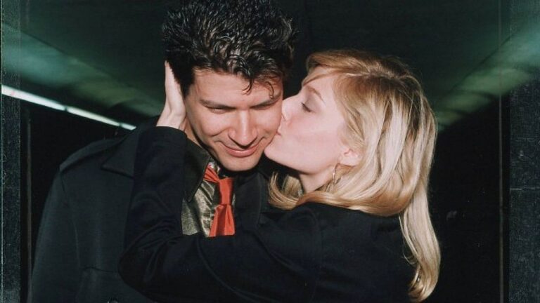 Mulher beija homem no rosto enquanto segura sua cabeça em cena de relacionamento romântico