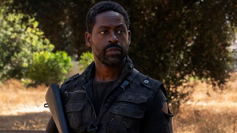 Homem com roupa tática segura arma e observa atento em área de mata em cena de série de ação