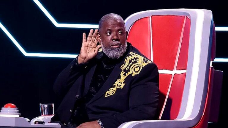 Jurado levanta a mão junto ao ouvido em cadeira do The Voice durante audição às cegas