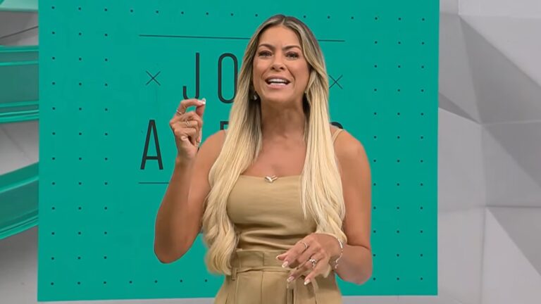 Renata Fan fala e gesticula no estúdio do programa Jogo Aberto, da Band, com telão verde ao fundo exibindo nome da atração.