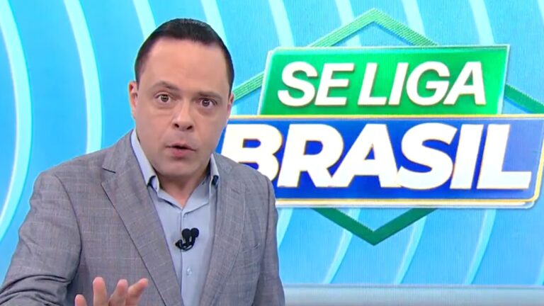 Thiago Gardinali, apresentador do Se Liga, Brasil, fala ao vivo em estúdio com logotipo do programa ao fundo.