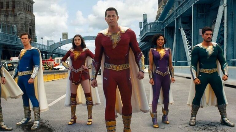 Shazam e equipe de heróis posam com uniformes coloridos em rua após ação em cena de filme