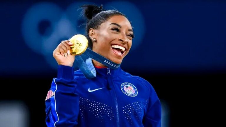 Ginasta exibe medalha de ouro das Olimpíadas de Paris 2024 com uniforme dos Estados Unidos sorrindo