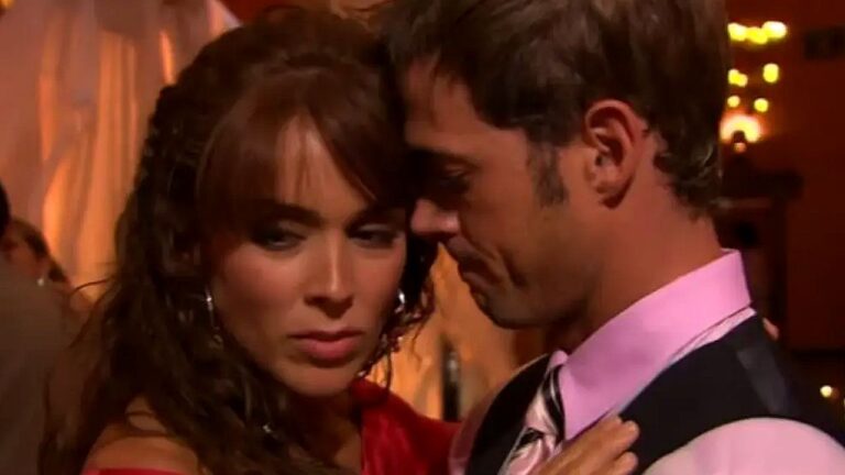 Casal dança junto em clima romântico com rostos próximos em cena de novela em ambiente com luz baixa