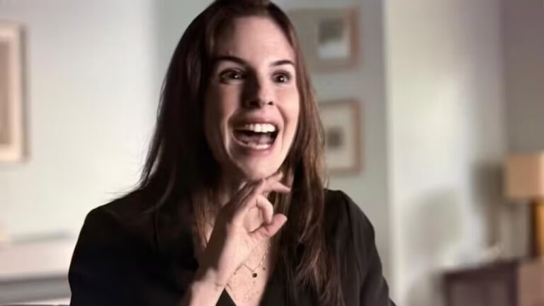 Suzane von Richthofen fala com expressão exaltada em ambiente interno com quadros na parede ao fundo