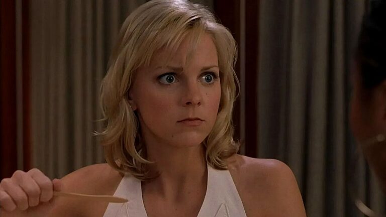 Mulher loira com expressão surpresa segura hashis durante refeição em cena de série ou filme