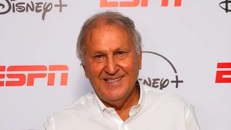 Zico sorri e aponta para logotipo da ESPN em painel de evento com marcas Disney+ e ESPN ao fundo