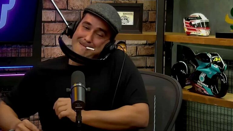 André Marques participa de podcast com fones e microfone diante de prateleira com capacetes esportivos