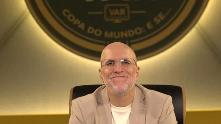 Antonio Tabet sentado em estúdio esportivo com logotipo ao fundo durante transmissão