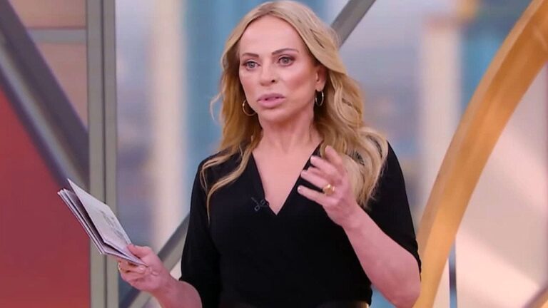 Apresentadora loira segura papéis durante programa matinal em estúdio de televisão