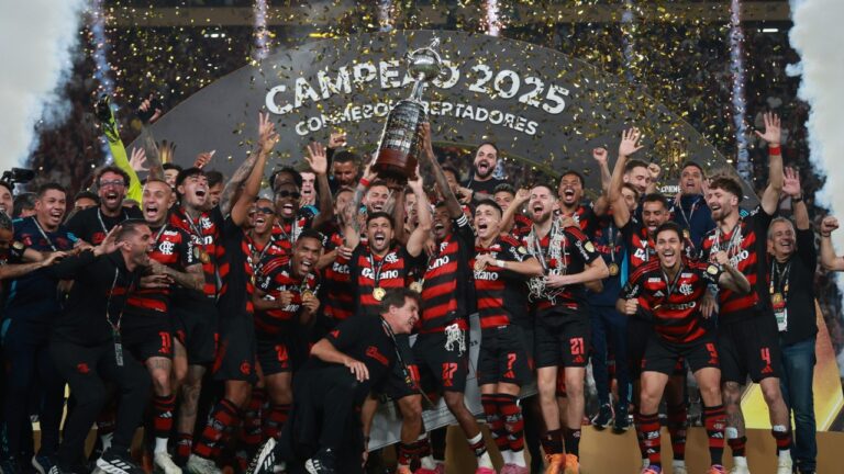 Jogadores do Flamengo erguem taça da Libertadores 2025 durante comemoração com confetes e fumaça no estádio
