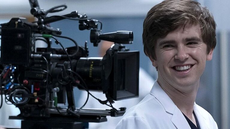 Freddie Highmore sorri ao lado de câmera nos bastidores da série The Good Doctor